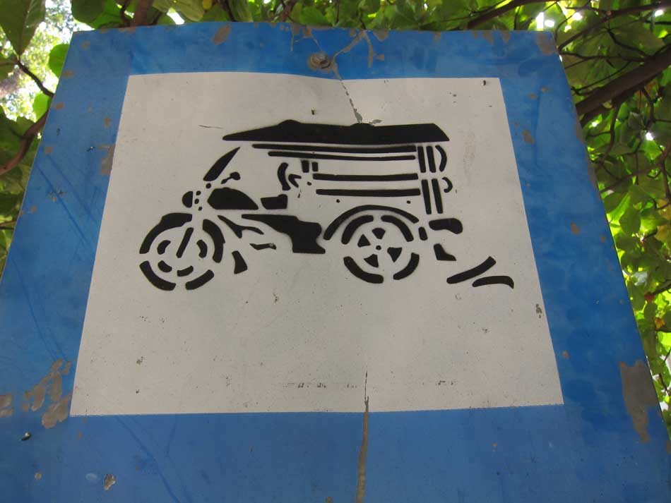 Panneau de signalisation routière avec un tuk tuk dessiné au pochoir